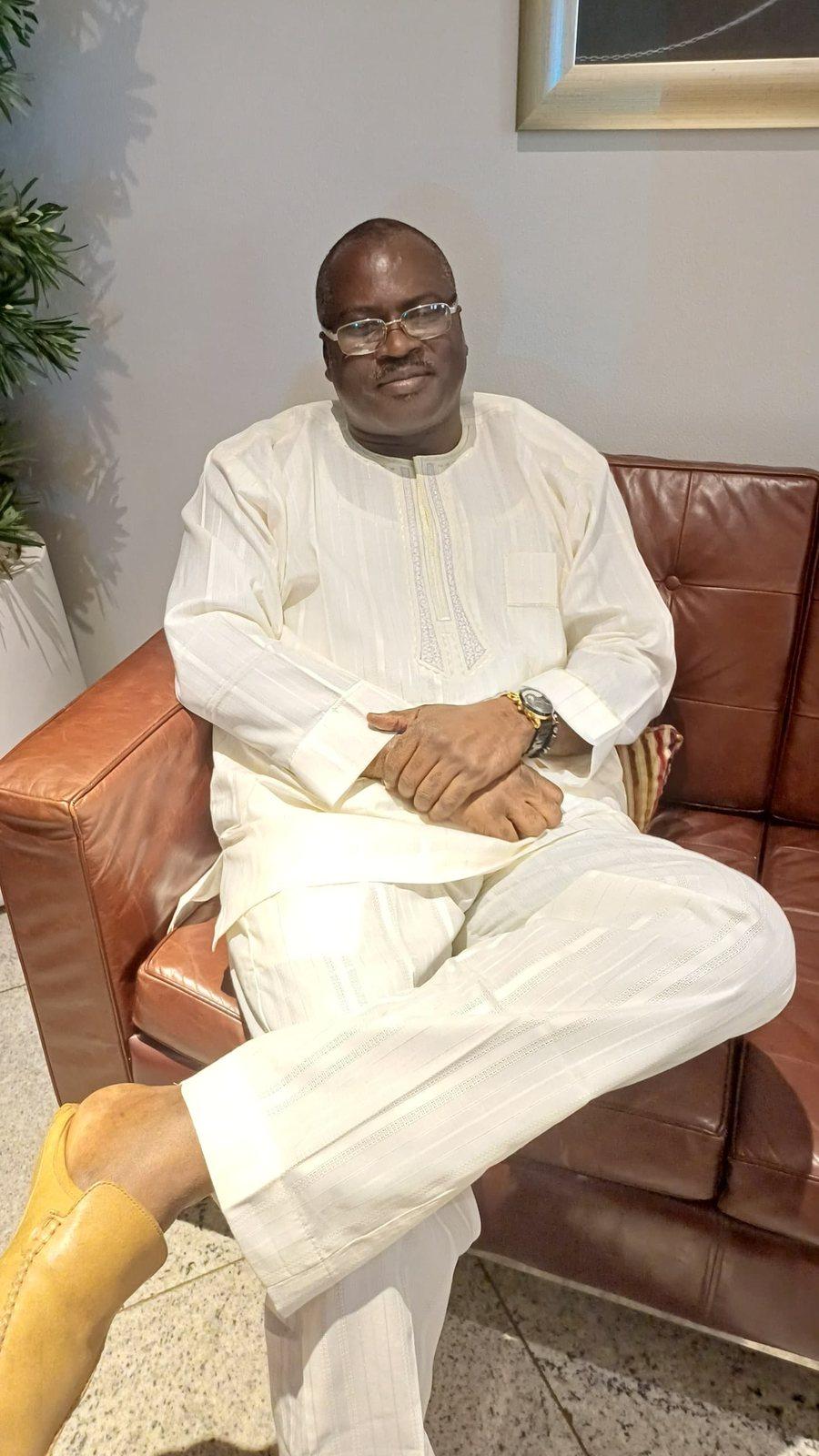 Padre Mike seated, dressed in white